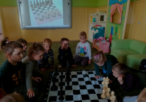 Dzieci oglądają planszę szachownicy i figury szachowe